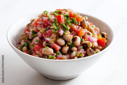 Fresh black-eyed pea salad with colorful vegetables served in a white bowl on a simple background during daylight