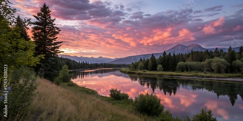 Vibrant sunset paints the sky with fiery hues reflecting in a serene river surrounded by lush forests and majestic mountains