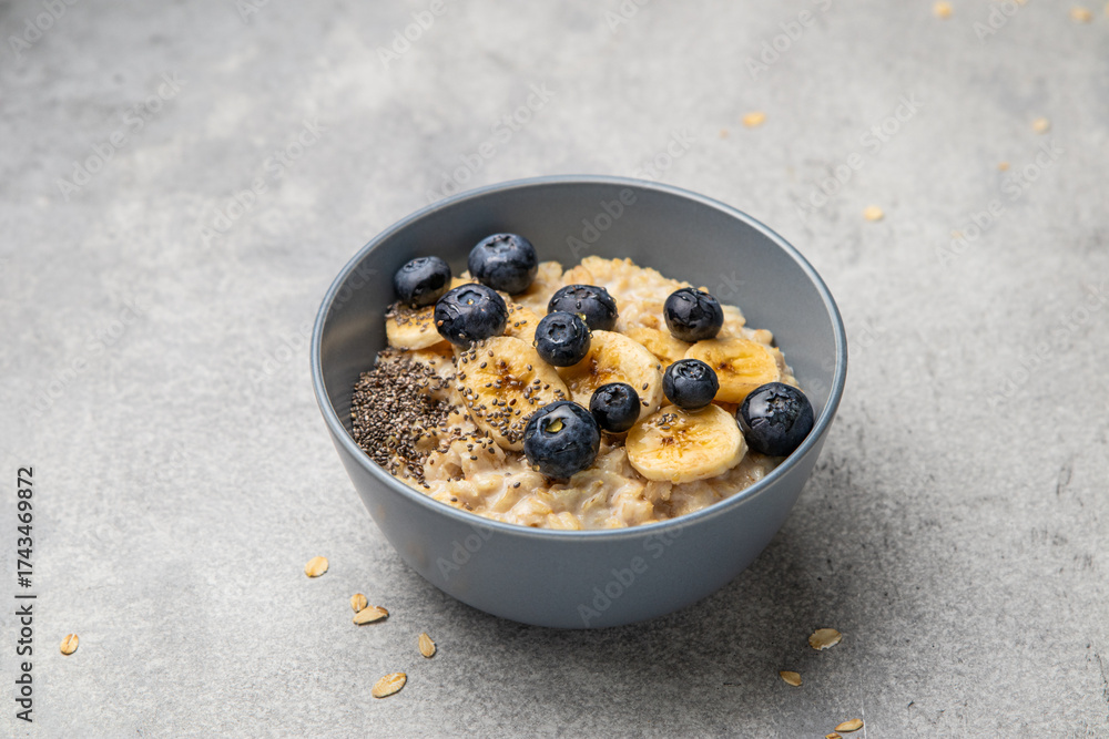 custom made wallpaper toronto digitalOatmeal porridge in bowl with milk, blueberries, banana, chia seeds and honey on a grey background. Healthy breakfast homemade food. Home cooking. Selective focus.