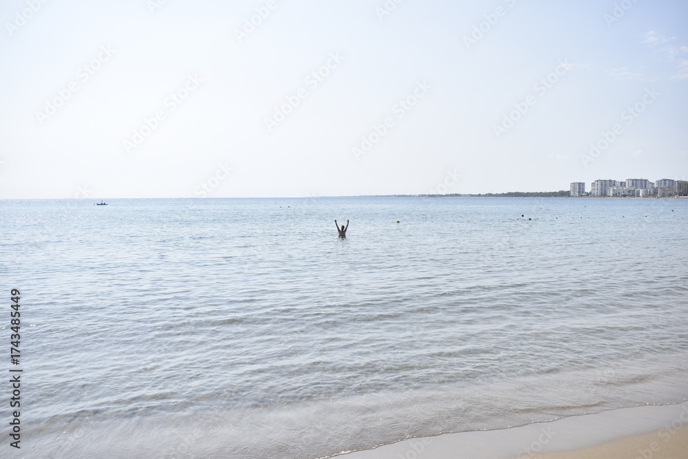 Obraz premium view of the sea, the horizon and a man in the distance with his hands raised from the shore