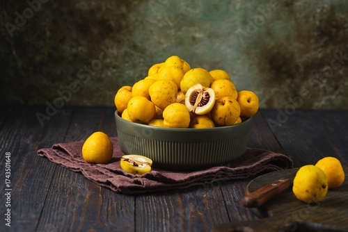 Japanese quince fruits, or Chaenomeles, in a ceramic bowl against a dark wooden background.