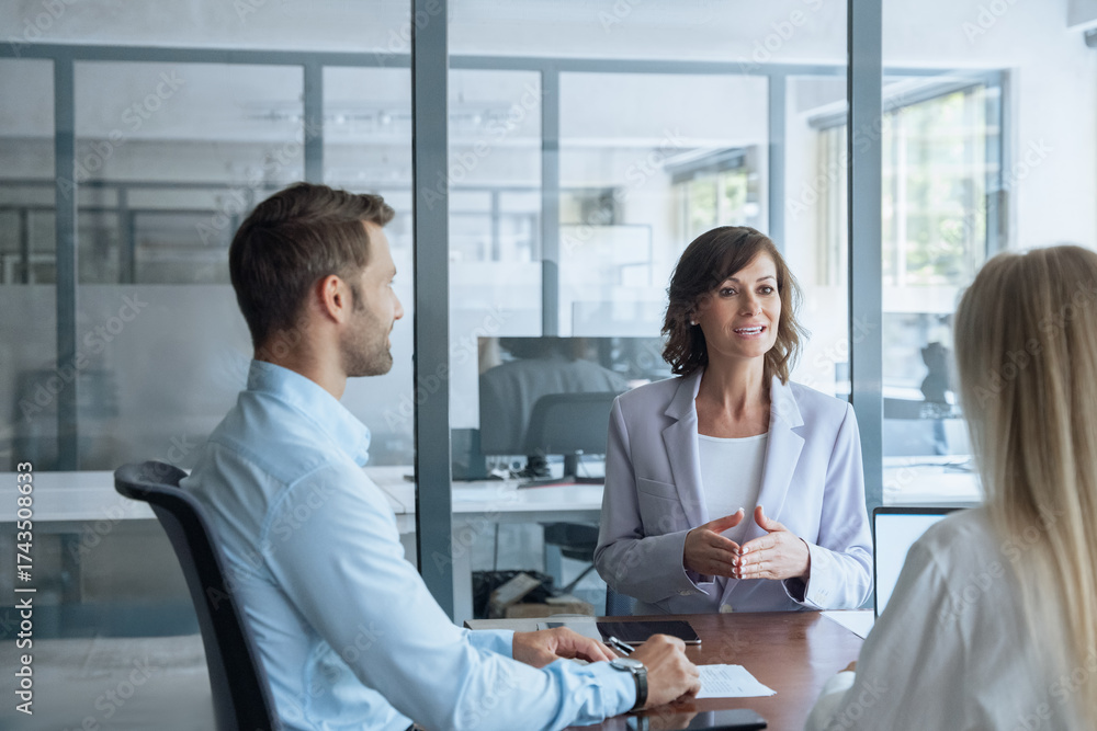 Fototapeta premium Meeting of professional business people working discussing financial trade strategy. Mature female mentor leader Latin woman collaborating with European young team talking about marketing in office.