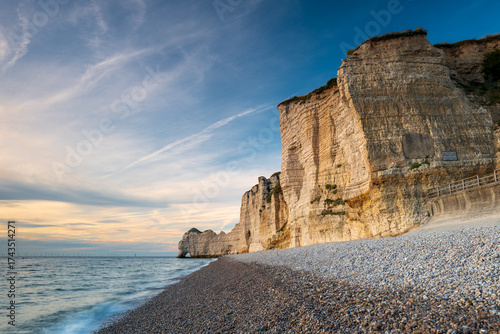 The Amont Cliffs and its pebble beach at sunset, city of Etretat, alabaster coast, department of Seine Maritime, Normandie region, France.
