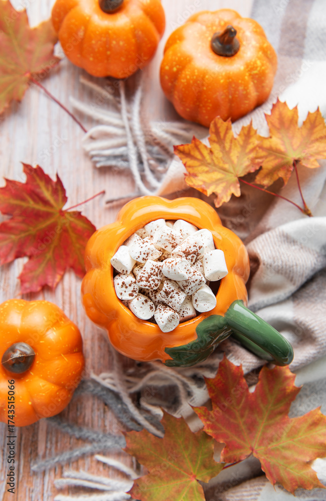 Fototapeta premium Pumpkin mug of hot chocolate with autumn leaves