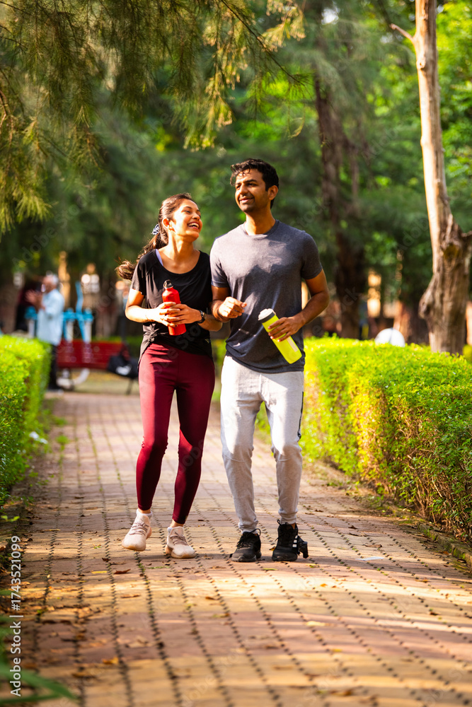 Obraz premium Indian young couple jogging in park enjoying morning fitness, outdoor freshness and bonding