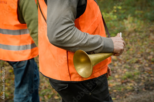 Cadrage serré sur la main d'un homme à la chasse qui tient une pibole ronde, instrument d'appel en vénerie