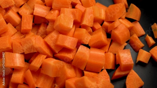 Pile of diced raw carrots on black ceramic plate. Chopped fresh vegetables. Macro. Top view
