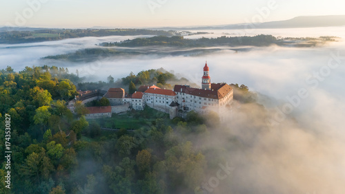 Náchod Castle at sunrise with fog in the valley engulfing the entire town of Náchod. Aerial view. Sunny summer or autumn day, Czech Republic