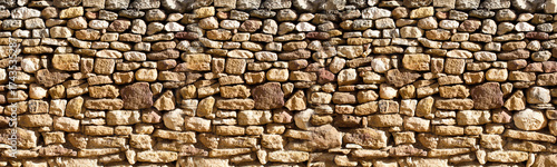 Rustic dry stone wall texture with natural earth tones. dry stone wall, showcasing irregular shapes and natural earthy colors. The texture is rough and organic.