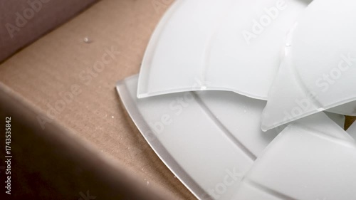 Broken lamp with glass shards in cardboard shipping box Failed delivery of fragile item concept