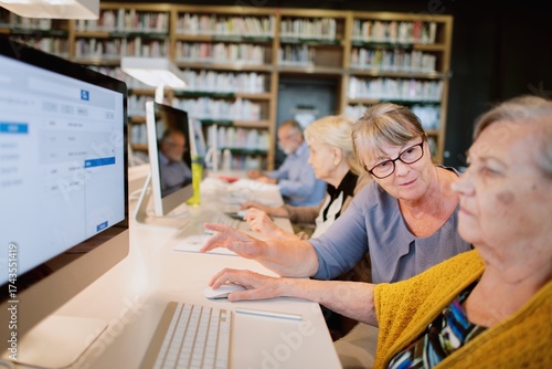 Картината върху платно Elderly women using computers in a library