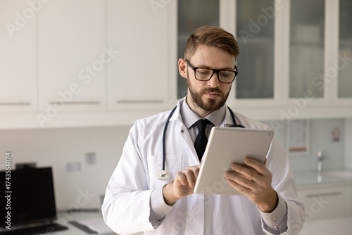 Obraz na plátně Physician preparing medical report, responding to patient messages using tablet