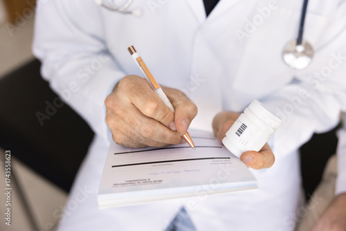 Fotografía Close up doctor holding medications bottle, writing on prescription pad