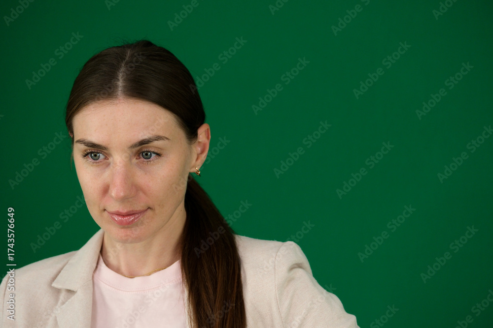 Fototapeta premium Professional photo collection of young European woman in light blazer with hair tied in ponytail and blue jeans on green chroma key background expressing different emotions and gestures perfect for ad