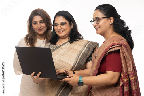 Three Indian confident woman working together with laptop on white