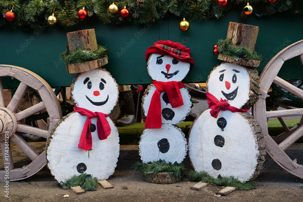 Fototapeta premium Three cheerful wooden snowmen are smiling. Snowmen are wearing hats and scarf