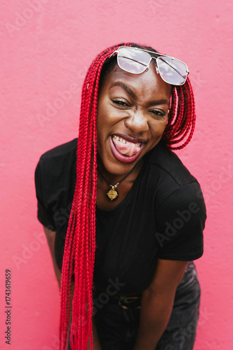 Smiling woman with red braids and sunglasses posing playfully