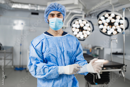 Fotografie A surgeon wearing a mask and surgical gown prepares for an operation in a modern operating room