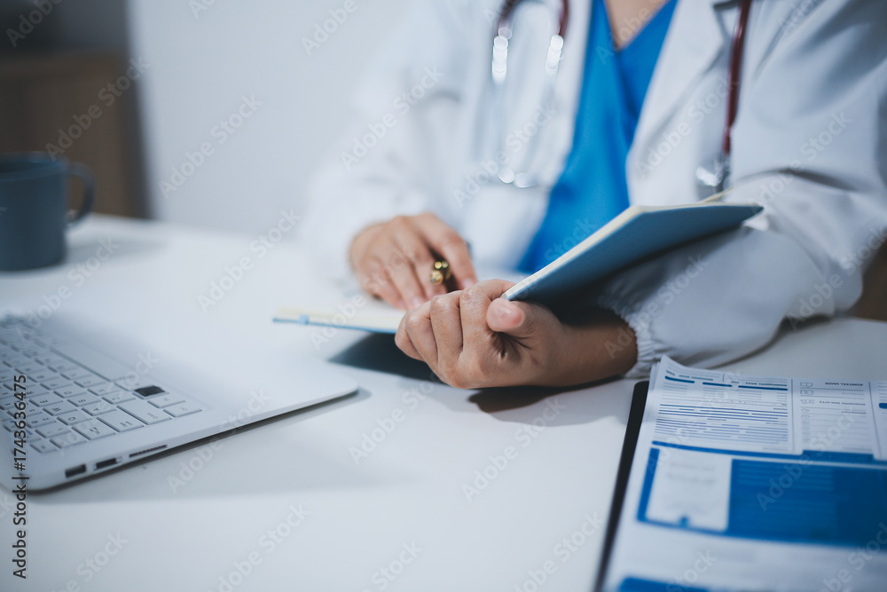 Fototapeta premium Middle aged female doctor working on laptop in doctor's room
