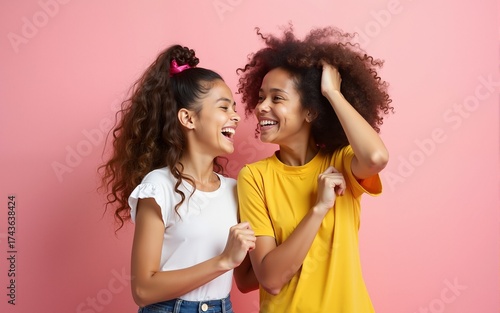 Good-humoured ladies expressing positive emotions. Studio portrait of two smiling girls dancing on pink background. High quality