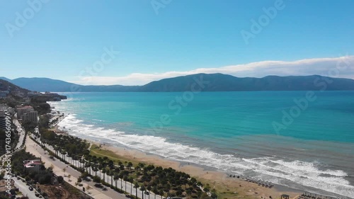 Aerial drone view of the stunning Albanian Riviera coastline, near the city of Vlora, Saranda showcasing pristine white beaches, turquoise sea water, cliffs and mountains under the Mediterranean sun.