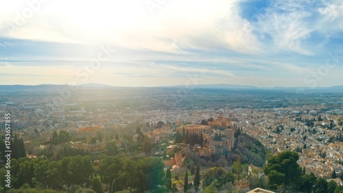 Granada Spain aerial sunny panorama with Alhambra fortress surrounded by lush gardens city rooftops Andalusian landmark UNESCO World Heritage site with Sierra Nevada mountains horizon view traveling
