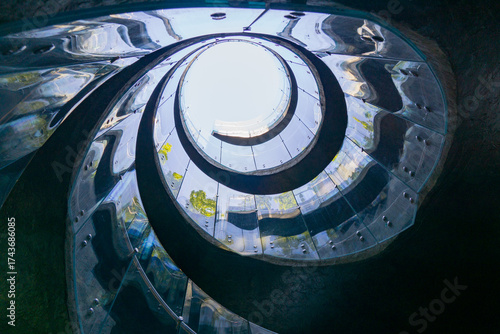 Tableau sur toile View of spiral glass staircase with reflective surfaces, leading upward through