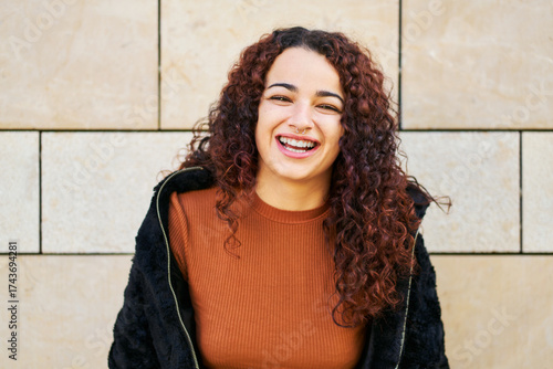 Happy young woman laughing with curly hair