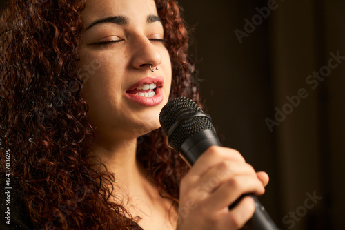 Woman with curly hair singing into microphone