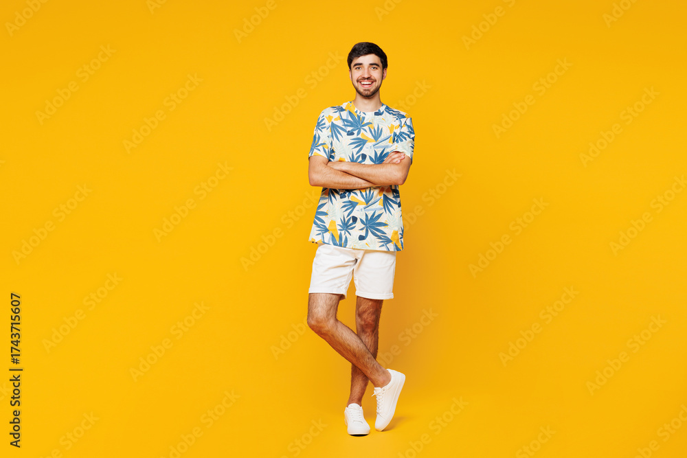 Fototapeta premium Full body young smiling happy Caucasian man wear blue beach t-shirt casual clothes hold hands crossed folded look camera isolated on plain yellow orange background studio portrait. Lifestyle concept.