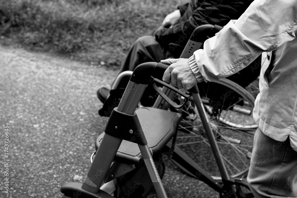 Obraz premium Elderly friends taking a walk in the park during cold weather with help of wheelchair and walker enjoying and having fun