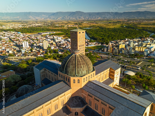 aerial view of the Basilica of the National Shrine of Our Lady Aparecida in Brazil during sunrise with mountains and greenery at distance
