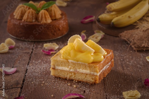 Slice of sponge cake topped with banana and creamy curd filling against a cake backdrop