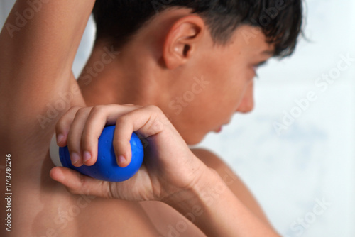 Hygiene, hormonal changes, and adolescence. Preteen boy applying deodorant to his armpit