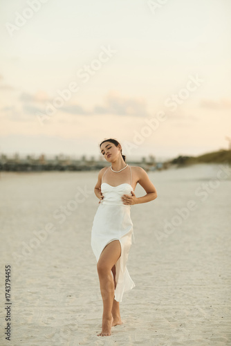 Young woman enjoying a summer evening on Miami beach in a beautiful slip dress