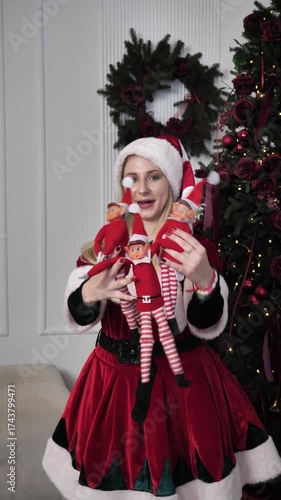 young woman in elf costume poses for cameras holding elf toys