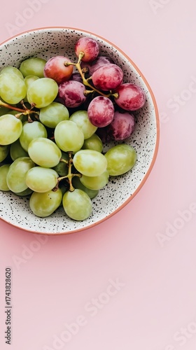 Studio-shot dessert styling featuring grapes in a china dish. The bright red and green tones contrast against a dotted backdrop for a clean, modern fruit arrangement.