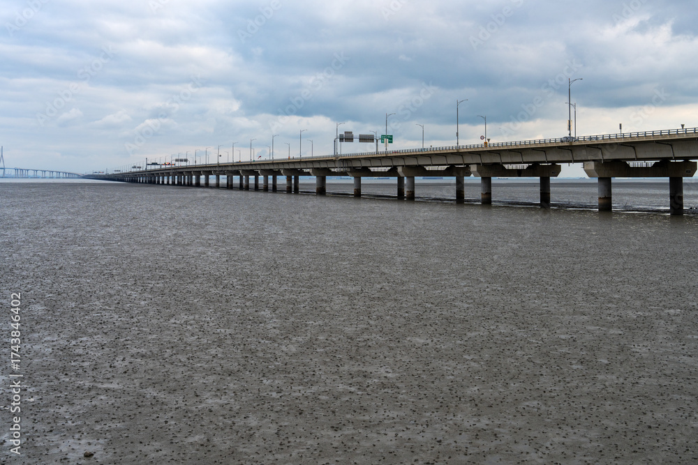 Obraz premium mudflat beach and long bridge on a cloudy day