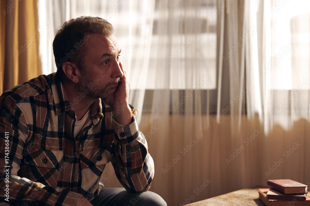 Fototapeta premium Man with depression and headache sitting on a chair at home.
