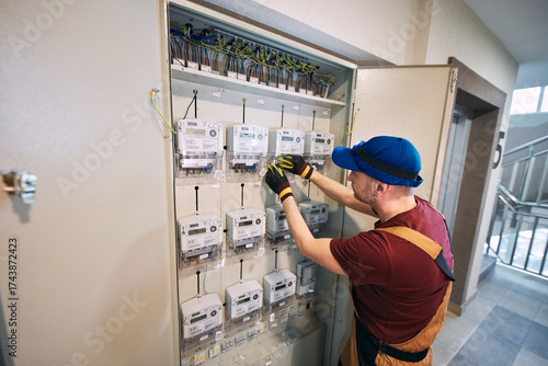 Electrician working on a modern electricity power meter station in a building.