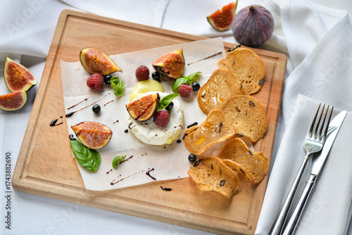figs drizzled with balsamic sauce on a wooden board with camembert cheese and bruschetta