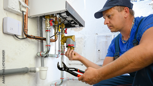 Plumber performing maintenance and repair on a modern home heating boiler