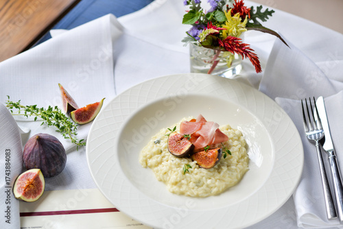 risotto with figs and ham in a white plate on a table with food decor