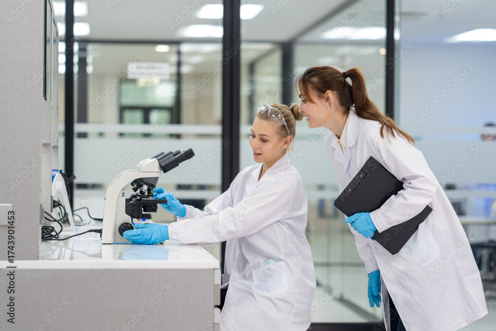 Fototapeta premium Scientists collaborate at a modern laboratory while analyzing samples under a microscope