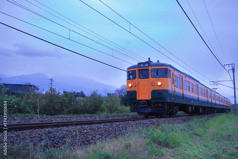 Naklejka premium 浅間山に見守られて曇天の軽井沢を走行するしなの鉄道115系電車(湘南色)_2025/10/4撮影