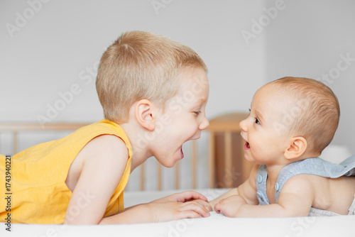 Cuadro en lienzo Two young brothers face-to-face on a bed, both with their mouths wide open in a moment of joyful interaction or playful shouting