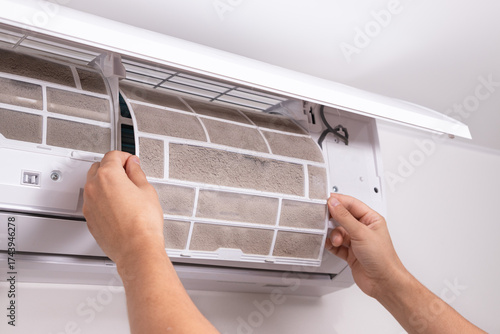 Man hand removing clogged air conditioner filter covered in dust and dirt. Concept of dirty indoor air, air purification, regular AC maintenance, and household hygiene.