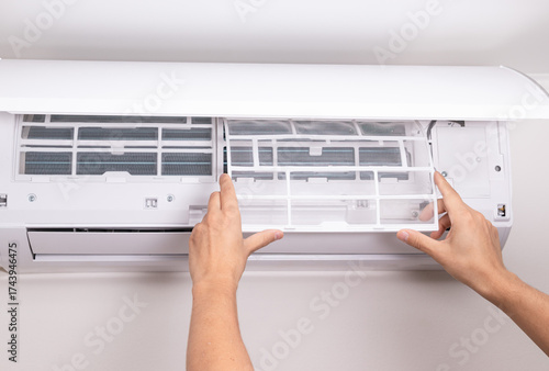 Hands of man installing new clean filter into split air conditioner. Concept of AC maintenance, indoor air quality, freshness, dust prevention, and efficient ventilation system.