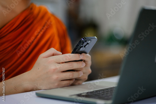 Foto Monks and priests, men in orange robes, use smartphones with white screens