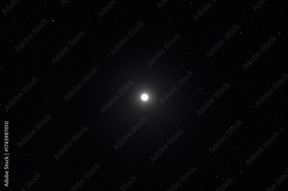 Fototapeta premium Long-range shot capturing a bright full moon against a dark, clear sky at night.